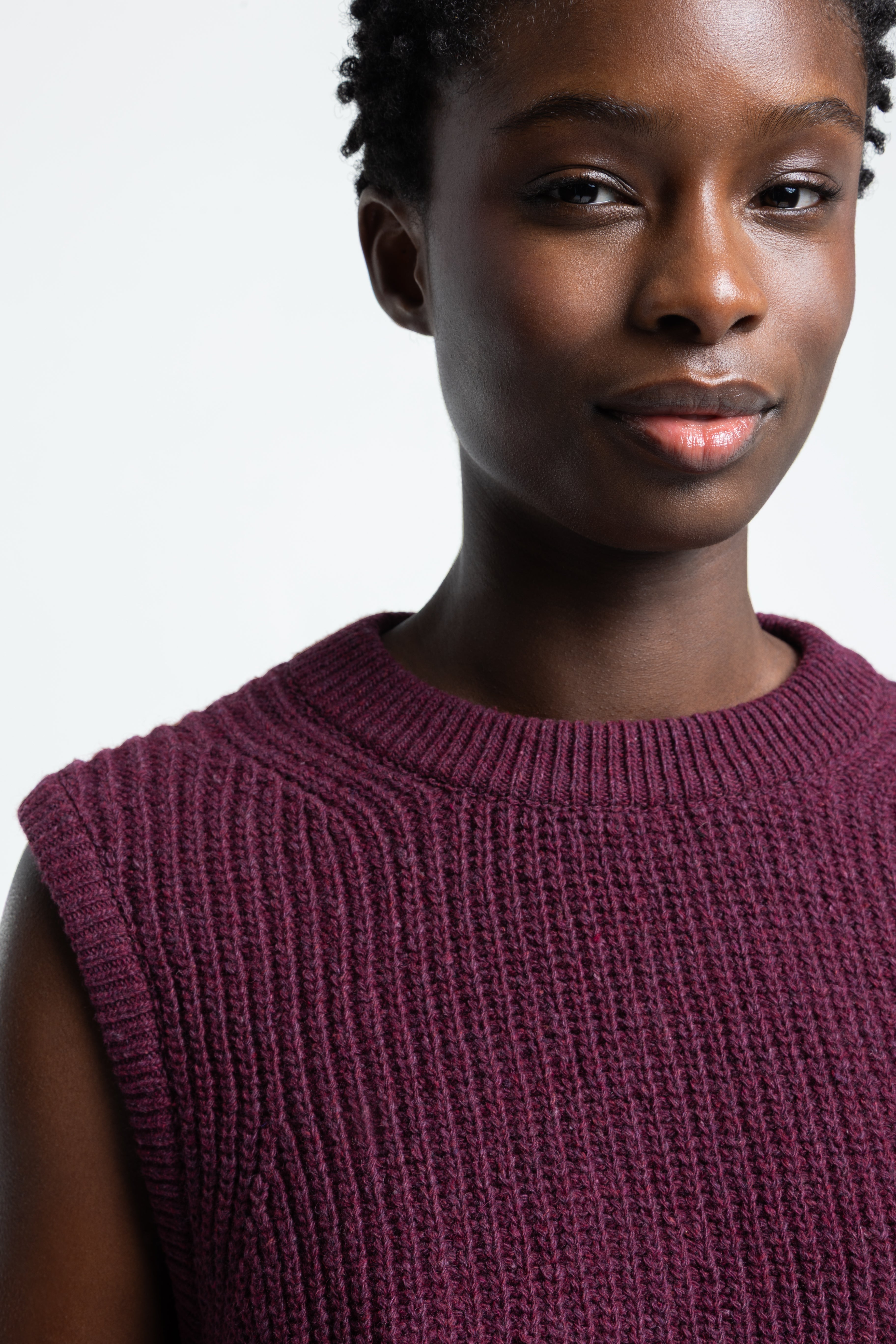 Woman wearing a purple sleeveless top against a plain background