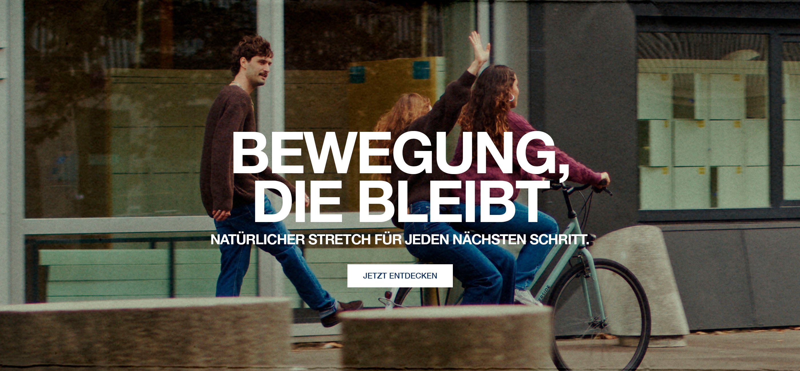 Two people with a bicycle on a city street, with text overlay in German.